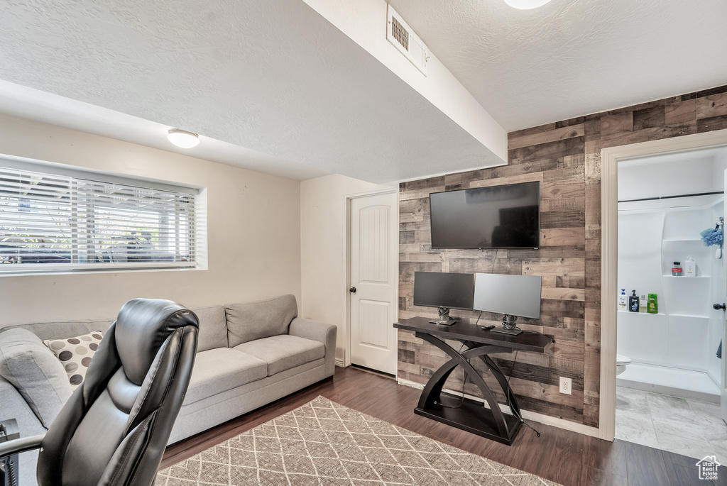 Office featuring visible vents, an accent wall, wood finished floors, wooden walls, and a textured ceiling