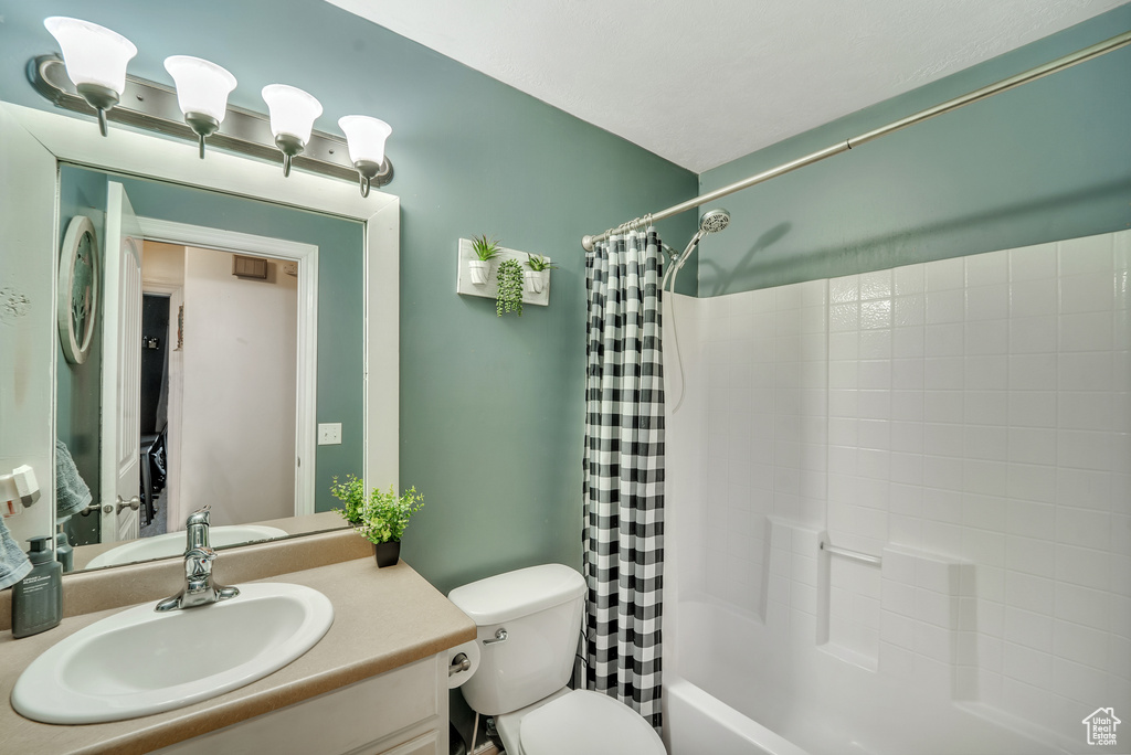 Full bathroom featuring vanity, shower / bath combination with curtain, and toilet