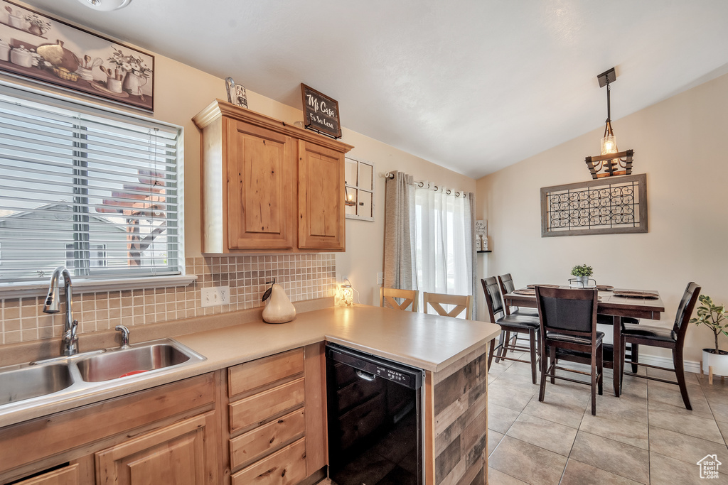Kitchen featuring decorative backsplash, a peninsula, lofted ceiling, light brown cabinetry, and a sink