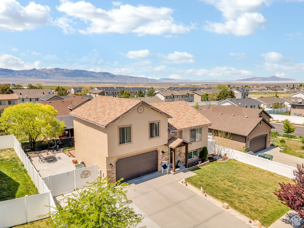 View of front of house featuring an attached garage, a residential view, a mountain view, and stucco siding