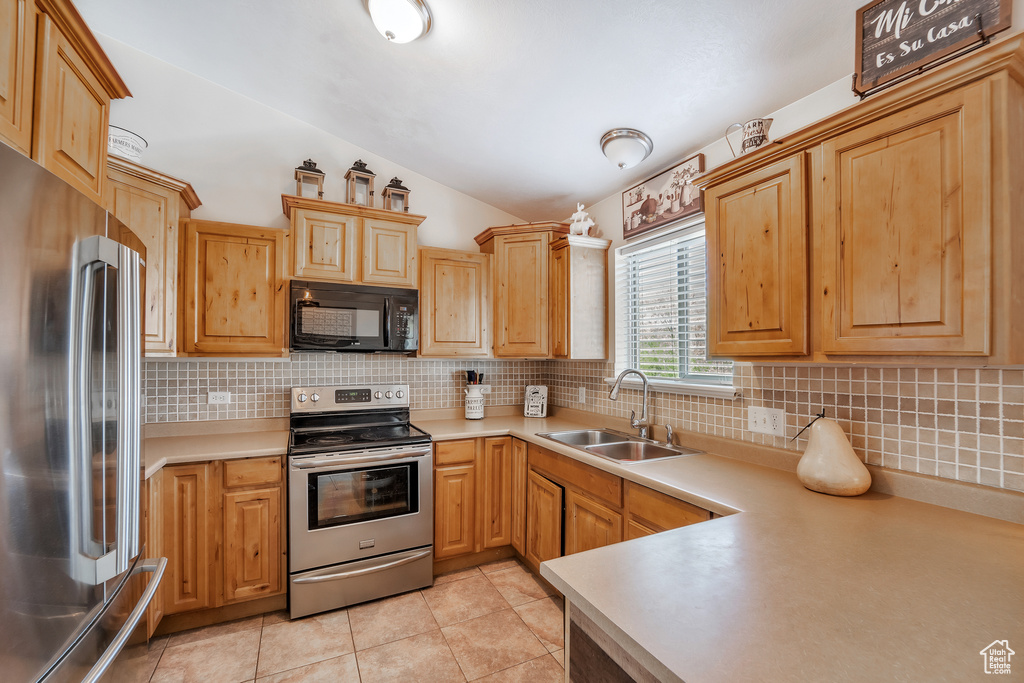 Kitchen with appliances with stainless steel finishes, a sink, light countertops, lofted ceiling, and tasteful backsplash