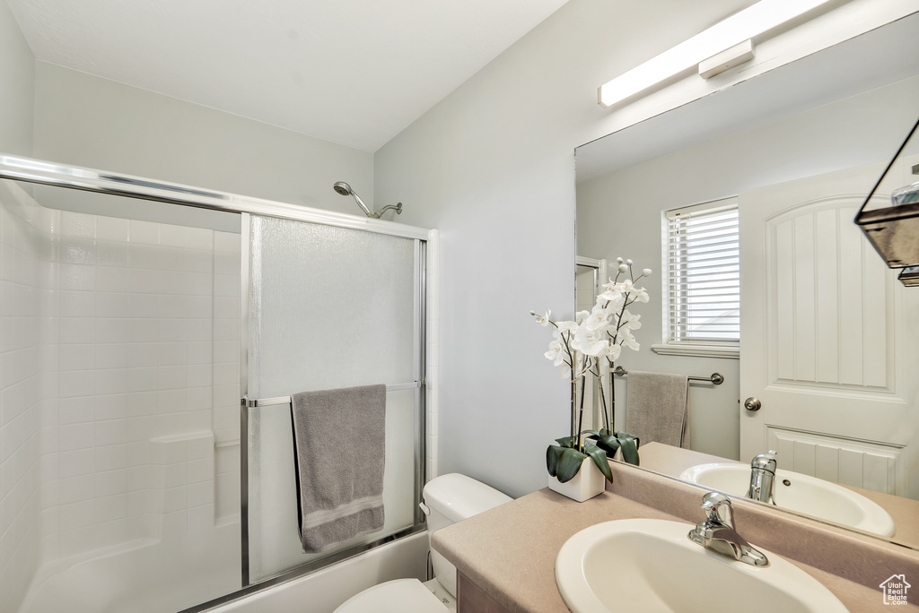 Bathroom with vanity, enclosed tub / shower combo, and toilet