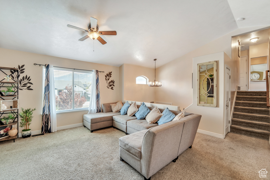 Living area with baseboards, lofted ceiling, carpet, and ceiling fan with notable chandelier