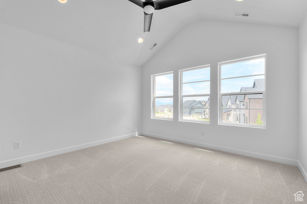 Empty room featuring a ceiling fan, healthy amount of natural light, vaulted ceiling, baseboards, and recessed lighting