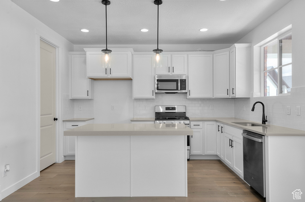 Kitchen featuring appliances with stainless steel finishes, a sink, white cabinetry, light wood-style flooring, and recessed lighting