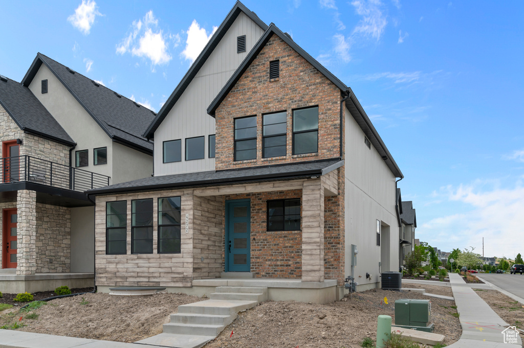 Contemporary home with central air condition unit, board and batten siding, a balcony, a porch, and stone siding
