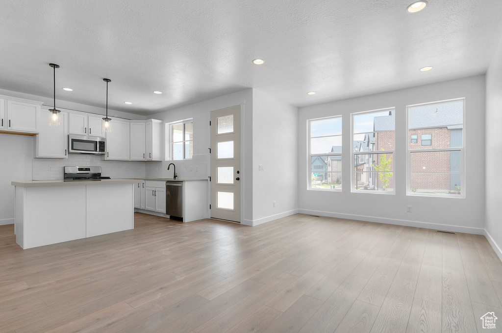 Kitchen with appliances with stainless steel finishes, backsplash, light countertops, recessed lighting, and baseboards