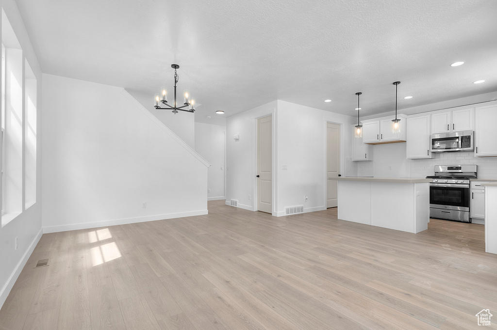 Unfurnished living room with light wood-style flooring, recessed lighting, a chandelier, and baseboards