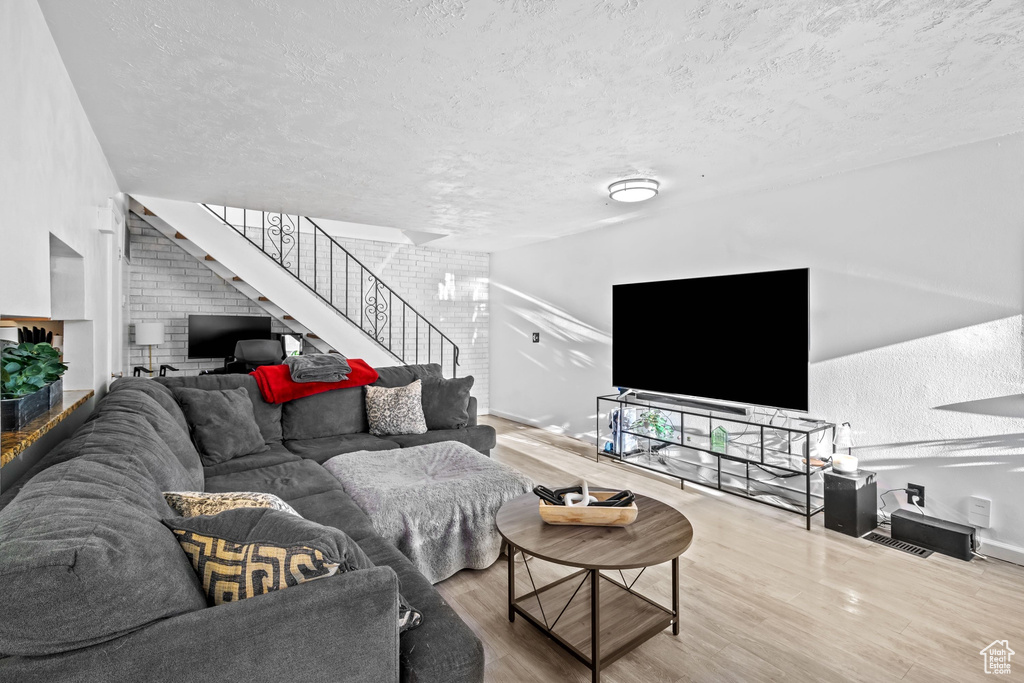 Living area featuring stairway, a textured ceiling, baseboards, and wood finished floors