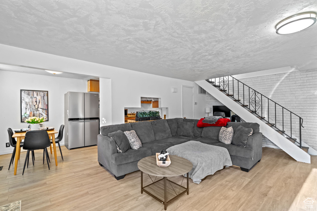 Living room featuring a textured ceiling, visible vents, stairway, and light wood-type flooring