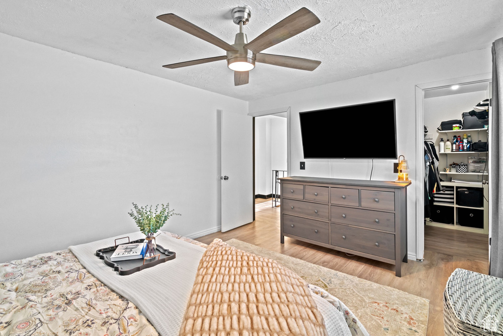 Bedroom featuring light wood-style floors, a textured ceiling, a spacious closet, and a closet