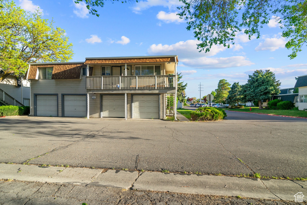 Front of property featuring mansard roof, driveway, a balcony, and a garage