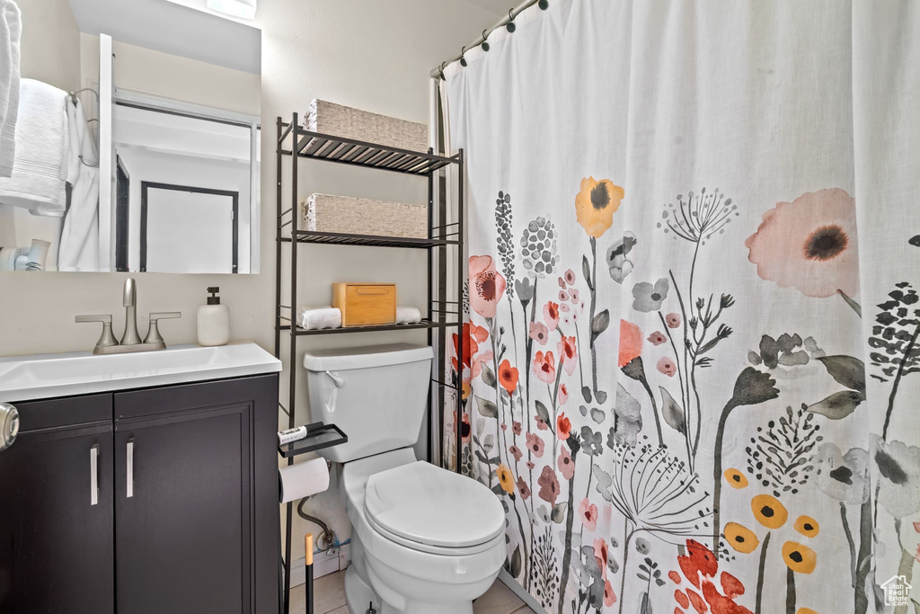Full bathroom featuring toilet, tile patterned floors, curtained shower, and vanity