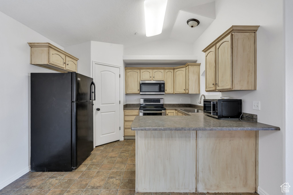 Kitchen featuring a peninsula, lofted ceiling, light brown cabinets, a sink, and black appliances