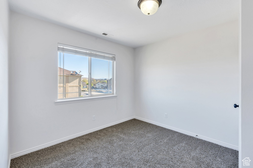 Unfurnished room featuring baseboards, visible vents, and carpet