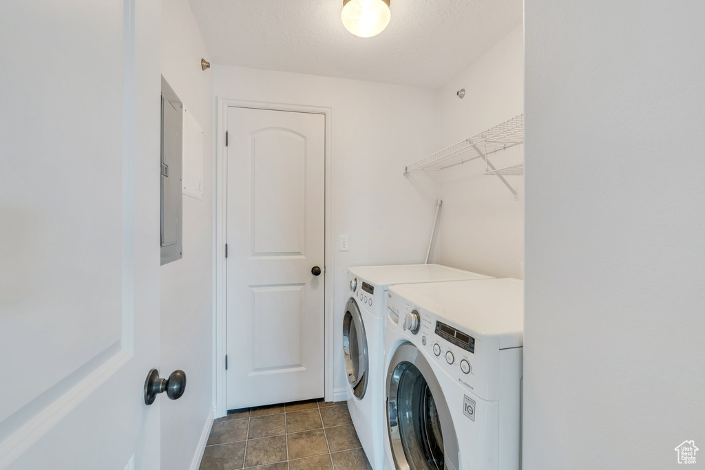 Washroom featuring laundry area, baseboards, electric panel, and washing machine and clothes dryer