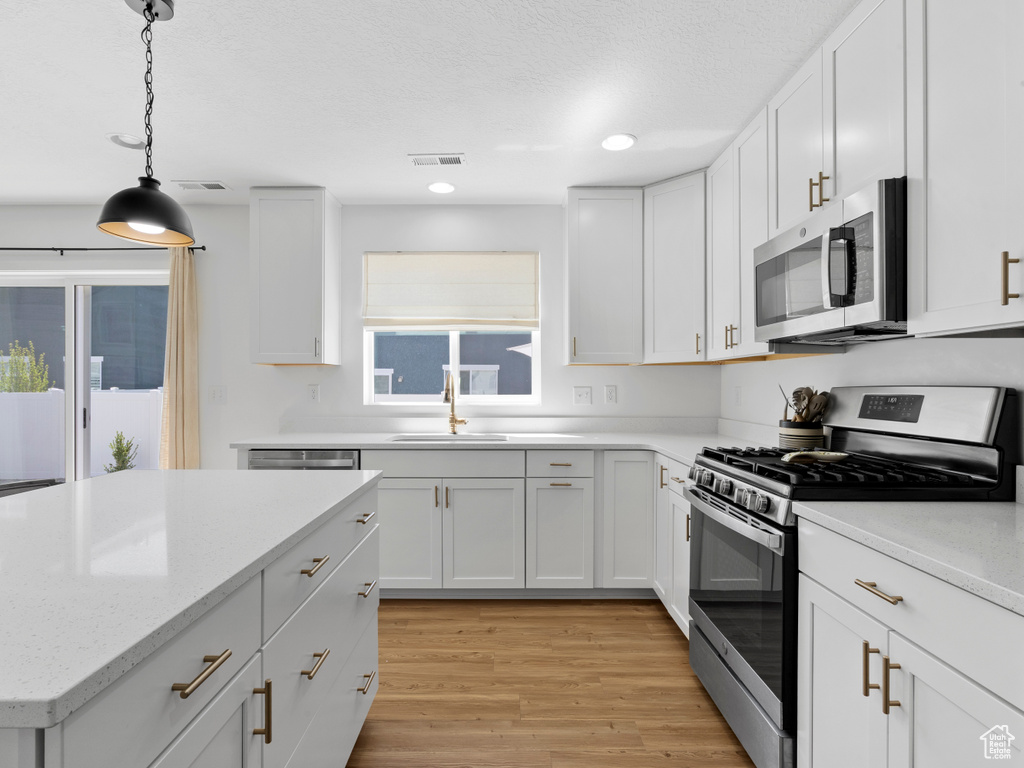 Kitchen featuring visible vents, light wood-type flooring, white cabinetry, a sink, and appliances with stainless steel finishes