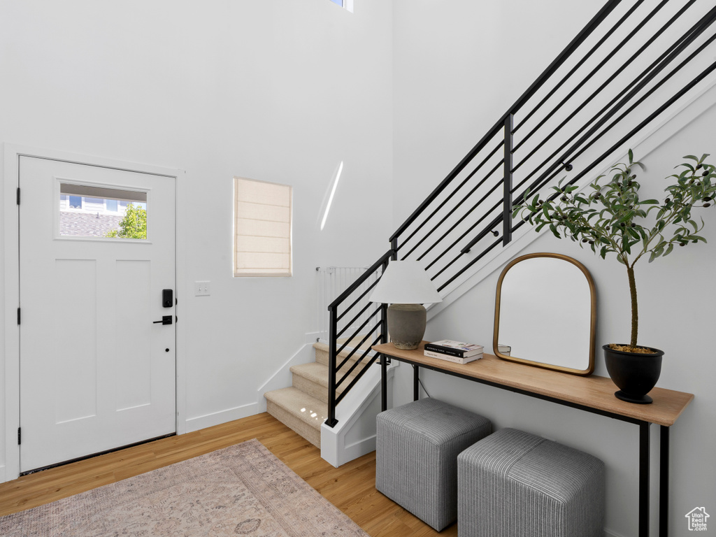 Foyer with light wood-style floors, baseboards, stairs, and a high ceiling