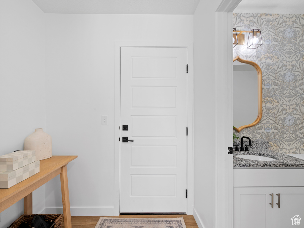 Doorway with a sink, baseboards, light wood finished floors, and wallpapered walls