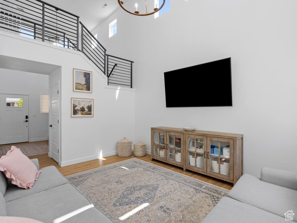 Living room with baseboards, a towering ceiling, wood finished floors, and an inviting chandelier