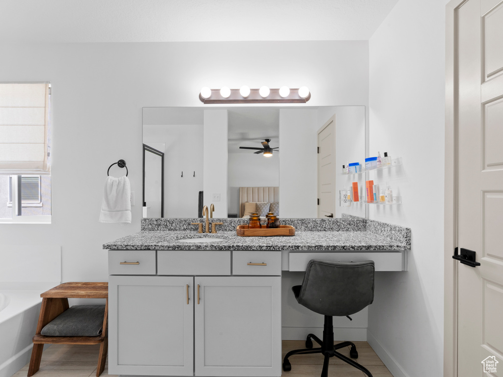 Bathroom with vanity, baseboards, a ceiling fan, and a garden tub