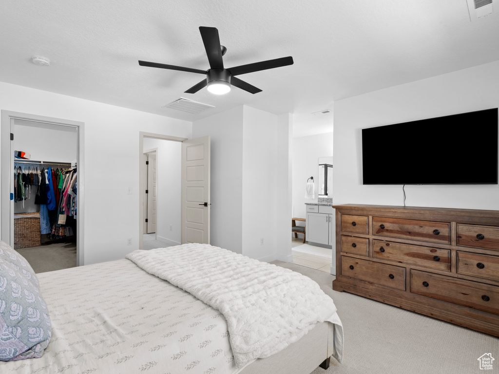 Bedroom featuring visible vents, a walk in closet, a closet, and light carpet