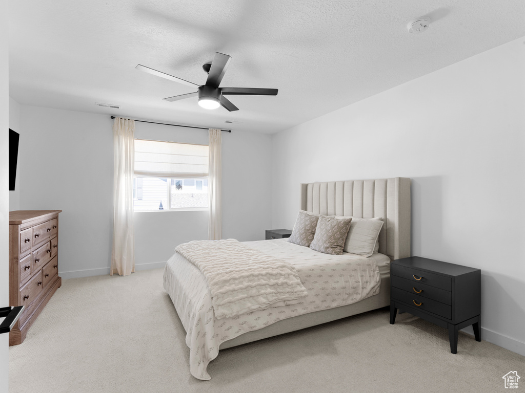 Bedroom with baseboards, visible vents, a ceiling fan, and light colored carpet