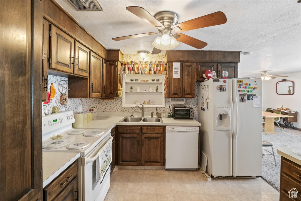 Kitchen featuring visible vents, a ceiling fan, white appliances, light countertops, and a sink