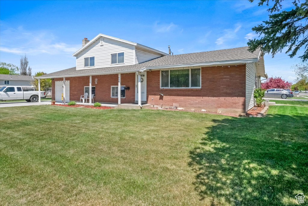 View of front of property featuring brick siding, a garage, a front yard, and a chimney