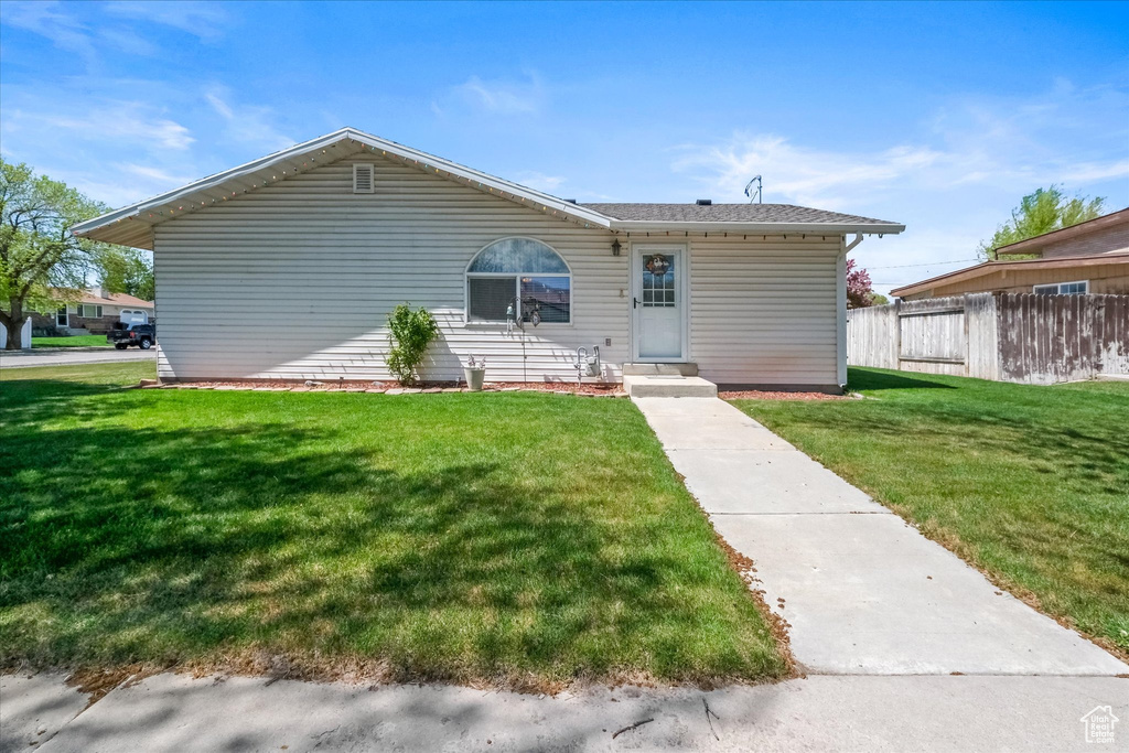 Rear view of house featuring a lawn and fence