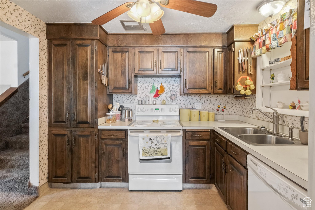 Kitchen featuring a sink, white appliances, light countertops, a ceiling fan, and wallpapered walls
