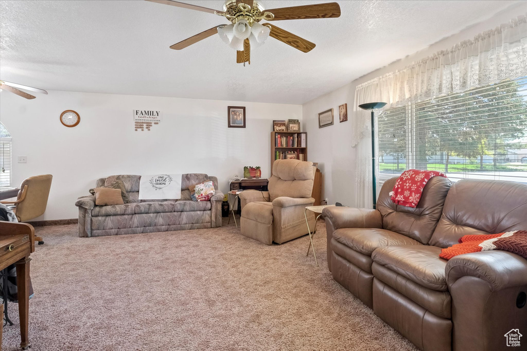 Carpeted living room with a ceiling fan