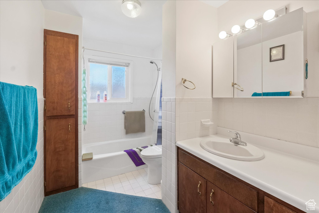 Bathroom with tile walls, tile patterned flooring, shower / tub combination, vanity, and toilet
