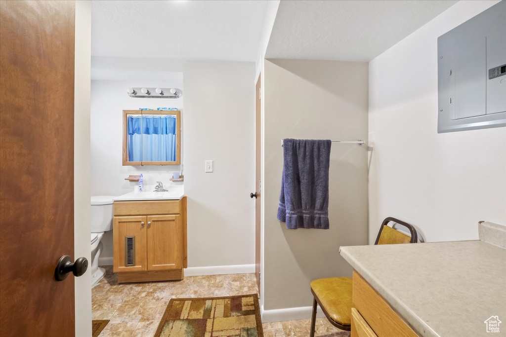 Bathroom with electric panel, visible vents, vanity, baseboards, and toilet