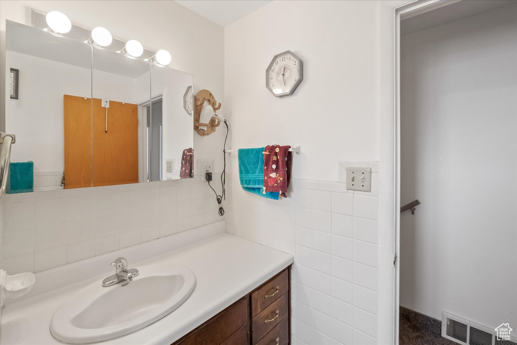 Bathroom with visible vents, vanity, and tile walls