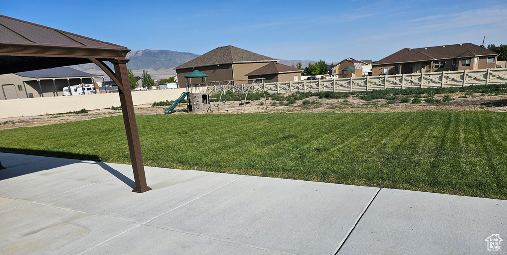 View of yard with a playground, a mountain view, and a patio area