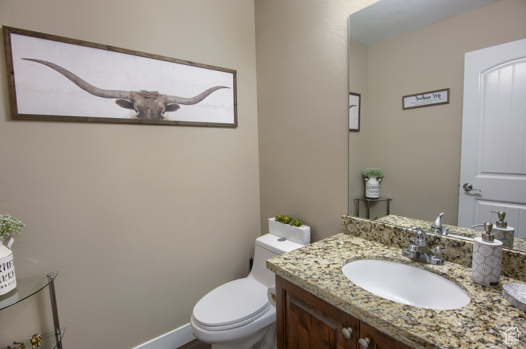 Bathroom featuring vanity, baseboards, and toilet