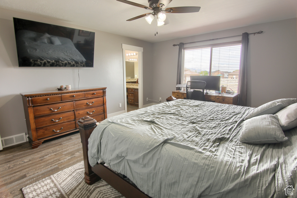 Bedroom featuring ceiling fan, ensuite bath, light wood-style floors, baseboards, and visible vents