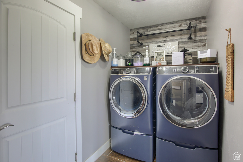 Laundry room featuring laundry area, independent washer and dryer, wood walls, wood finished floors, and baseboards