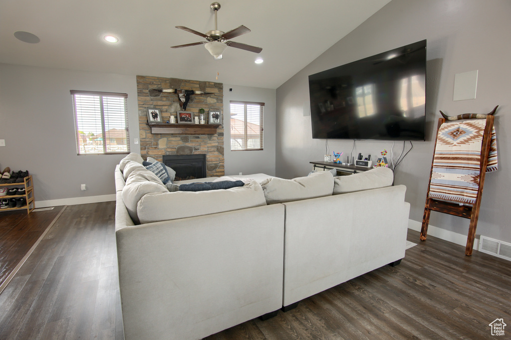 Living area with a ceiling fan, dark wood-style floors, a healthy amount of sunlight, and a fireplace