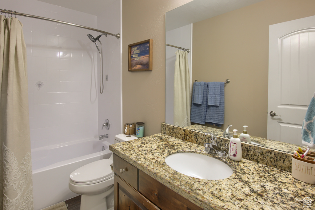 Bathroom featuring toilet, shower / tub combo with curtain, and vanity