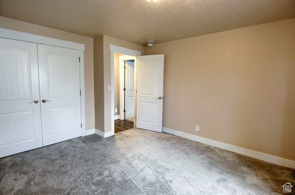 Unfurnished bedroom featuring baseboards, carpet, and a closet