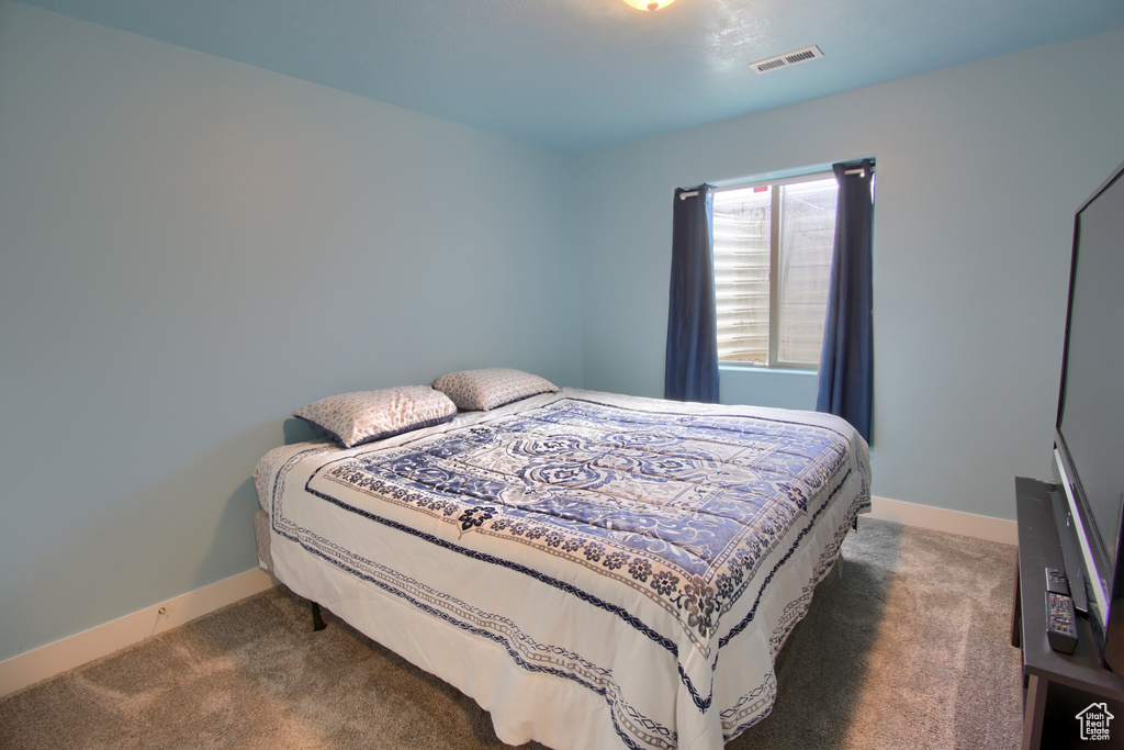 Bedroom featuring baseboards, dark colored carpet, and visible vents