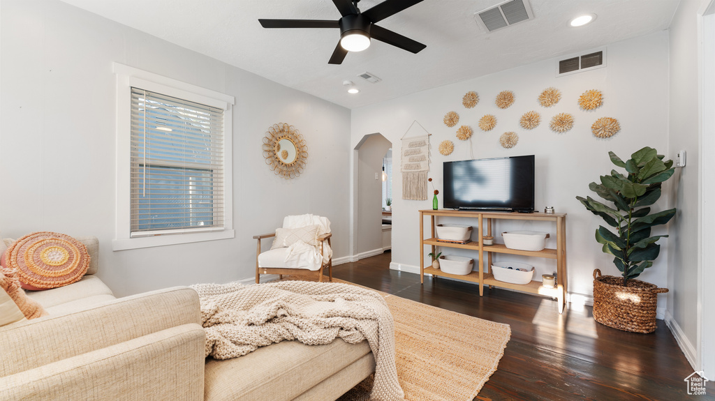 Living room with visible vents, a ceiling fan, dark wood-style flooring, and arched walkways