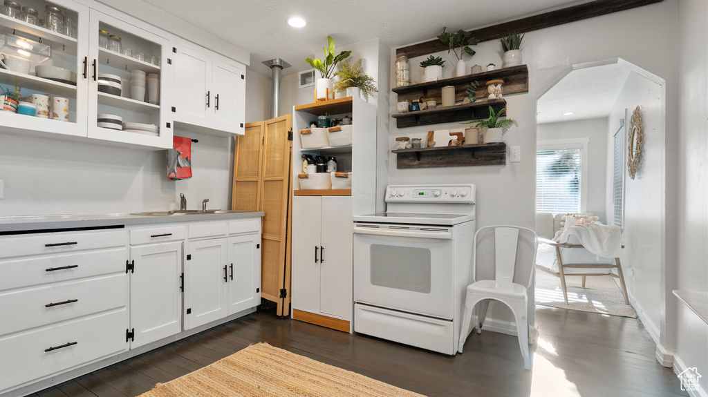 Kitchen with open shelves, dark wood-style flooring, glass insert cabinets, white electric range oven, and white cabinetry