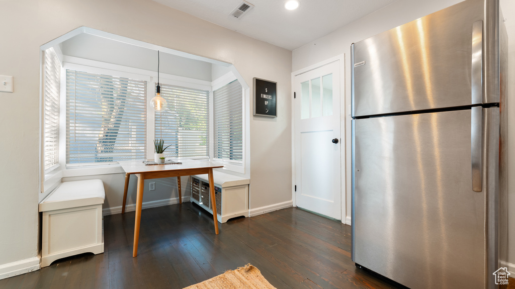 Kitchen with dark wood finished floors, freestanding refrigerator, baseboards, visible vents, and pendant lighting