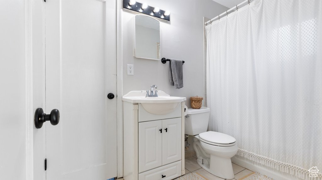 Bathroom featuring tile patterned floors, vanity, toilet, and curtained shower