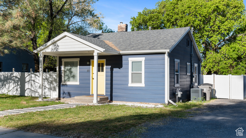 Bungalow featuring a shingled roof, a front lawn, fence, and a chimney