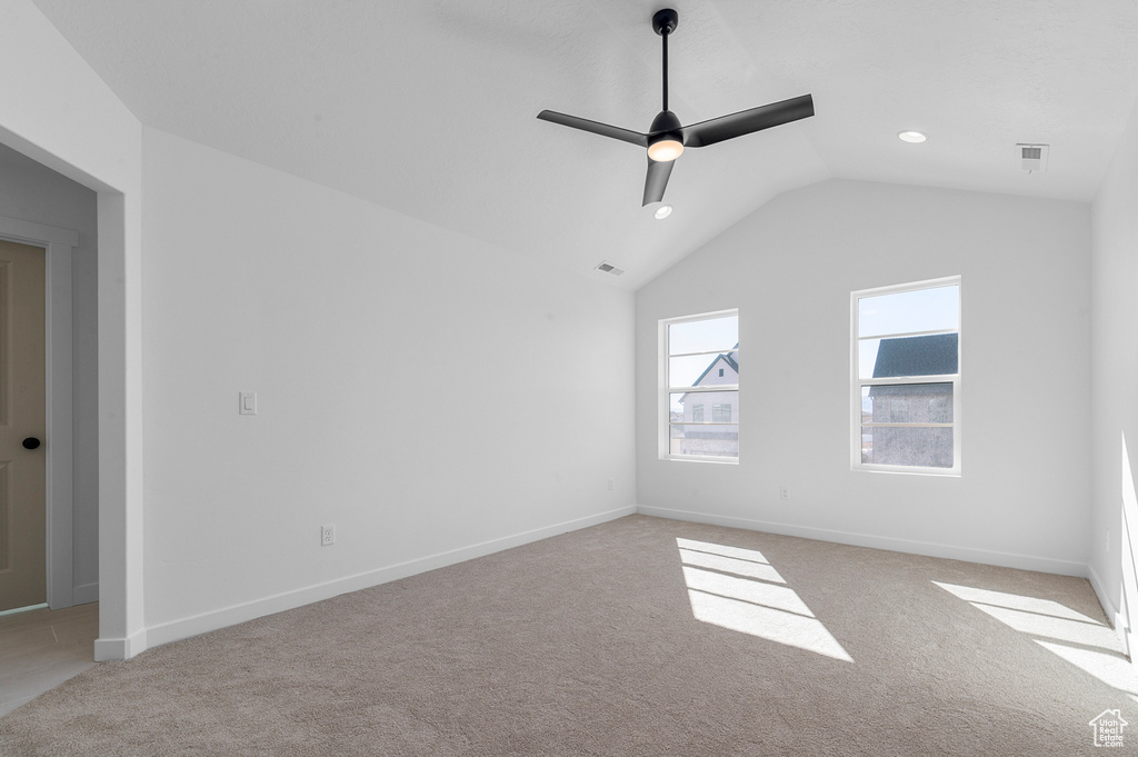 Unfurnished room with visible vents, baseboards, ceiling fan, carpet flooring, and vaulted ceiling