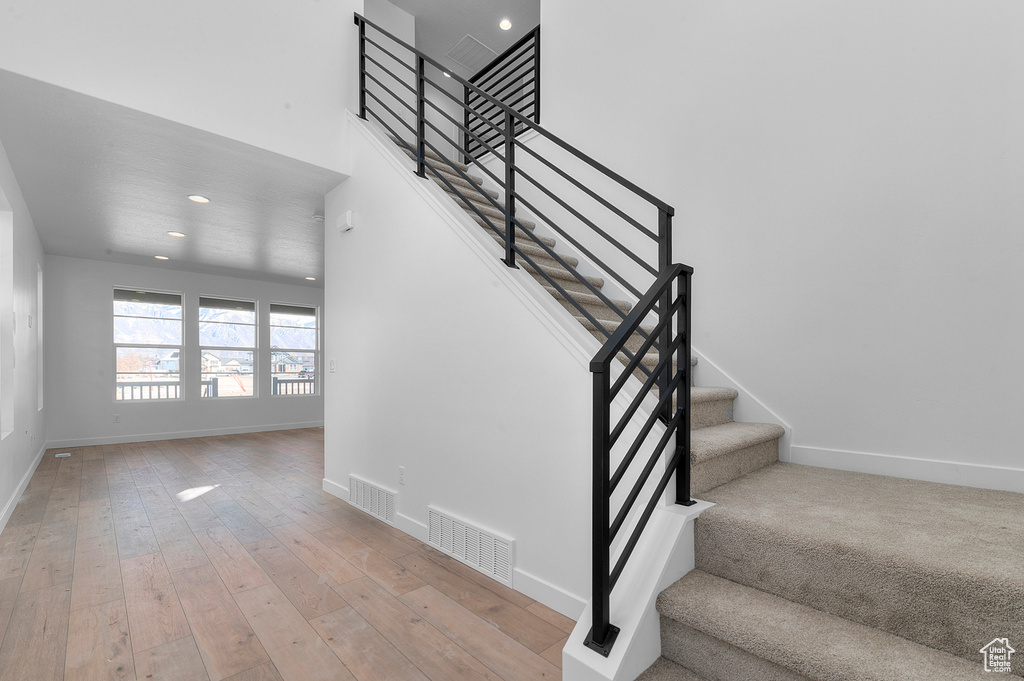Stairs featuring wood-type flooring, recessed lighting, baseboards, and visible vents
